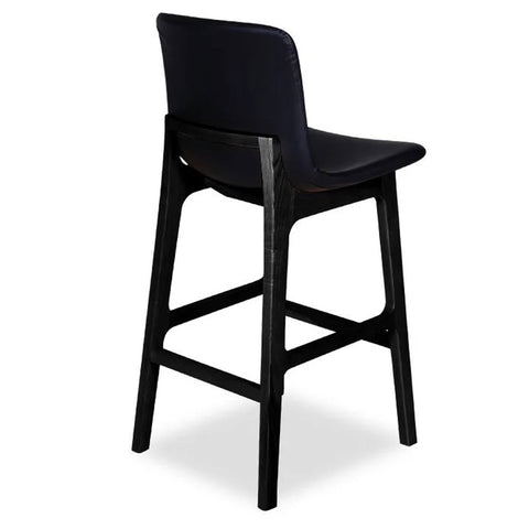 A black upholstered Ara stool with a contoured seat and wooden legs, viewed from the back.
