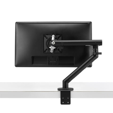 Flo single black monitor arm mounted on a desk with a monitor attached to it.