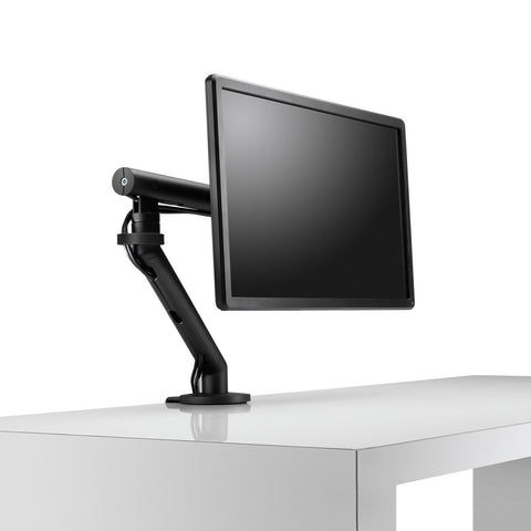 Flo single black monitor arm mounted on a desk with a monitor attached to it.