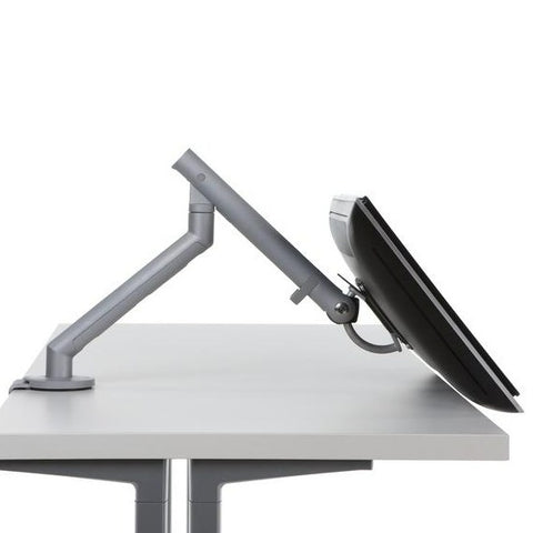 Side view of Flo single monitor arm mounted on a desk with a monitor, featuring adjustable length and angle