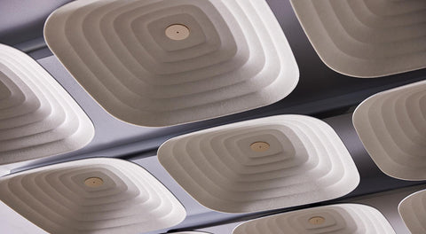 A close-up of Fuji Roku square beige 3D acoustic tiles with a woven pattern, fixed to the ceiling.