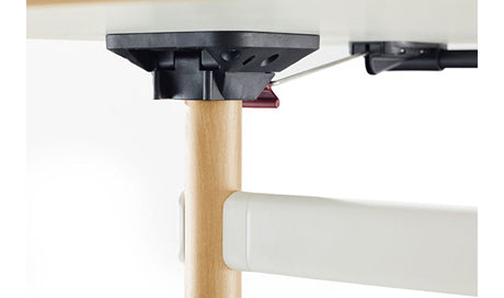 Close-up of Okidoki rectangle folding table showing white frame, ash wooden legs, and folding hinges.