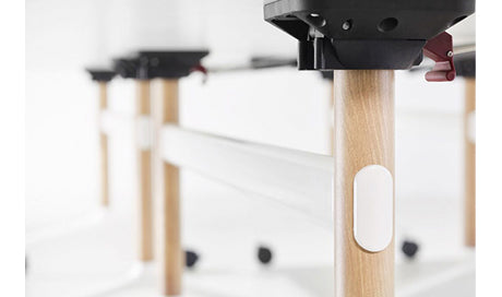 Close-up of Okidoki rectangle folding table showing white frame, ash wooden legs, and folding hinges.