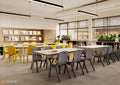 A modern classroom or study space with long rectangular tables and chairs. The foreground tables are paired with gray chairs, while the tables on the left are paired with bright yellow chairs.