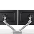 Flo dual monitor arm setup back view. The device is mounted on a desk clamp and features adjustable joints for angle and length customization.