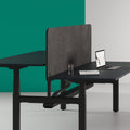 A modern office workstation featuring a black LOVOC worktop mounted upholstered screen